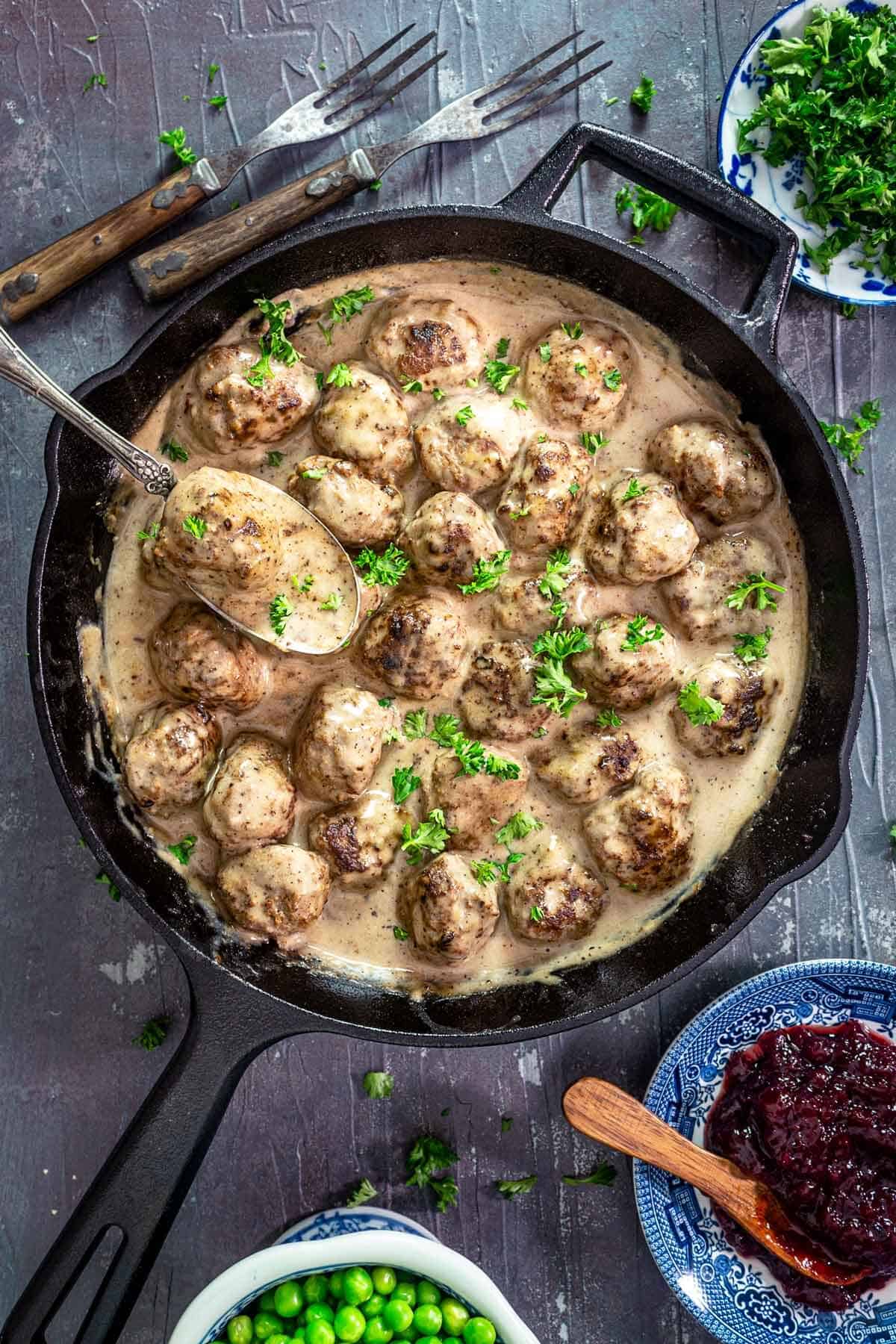 An overhead photo of cast-iron skillet with Swedish meatballs in a creamy gravy.