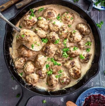 An overhead photo of cast-iron skillet with Swedish meatballs in a creamy gravy.