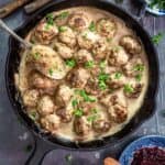 An overhead photo of cast-iron skillet with Swedish meatballs in a creamy gravy.