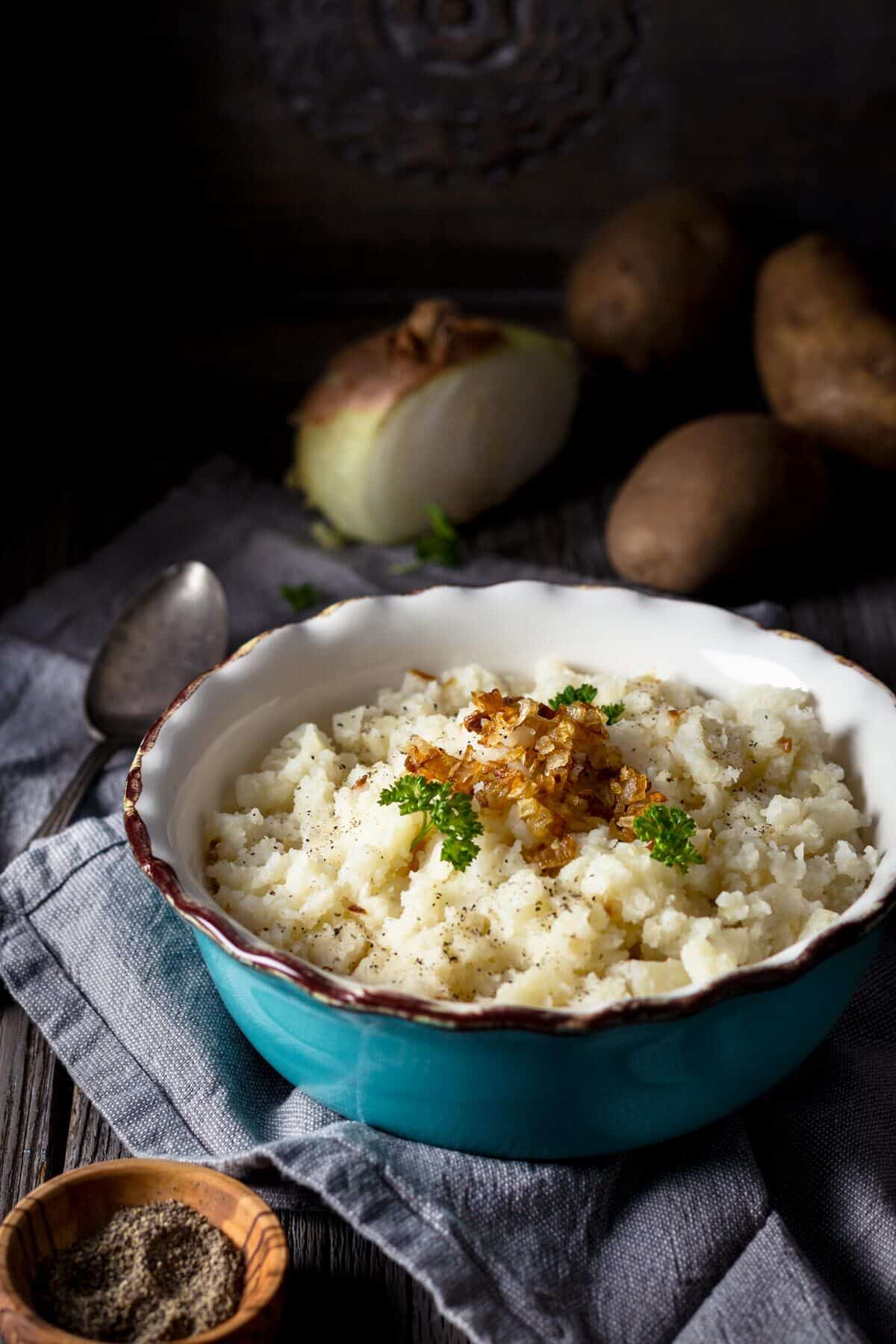 Dairy-free mashed potatoes in a bowl topped with caramelized onions.