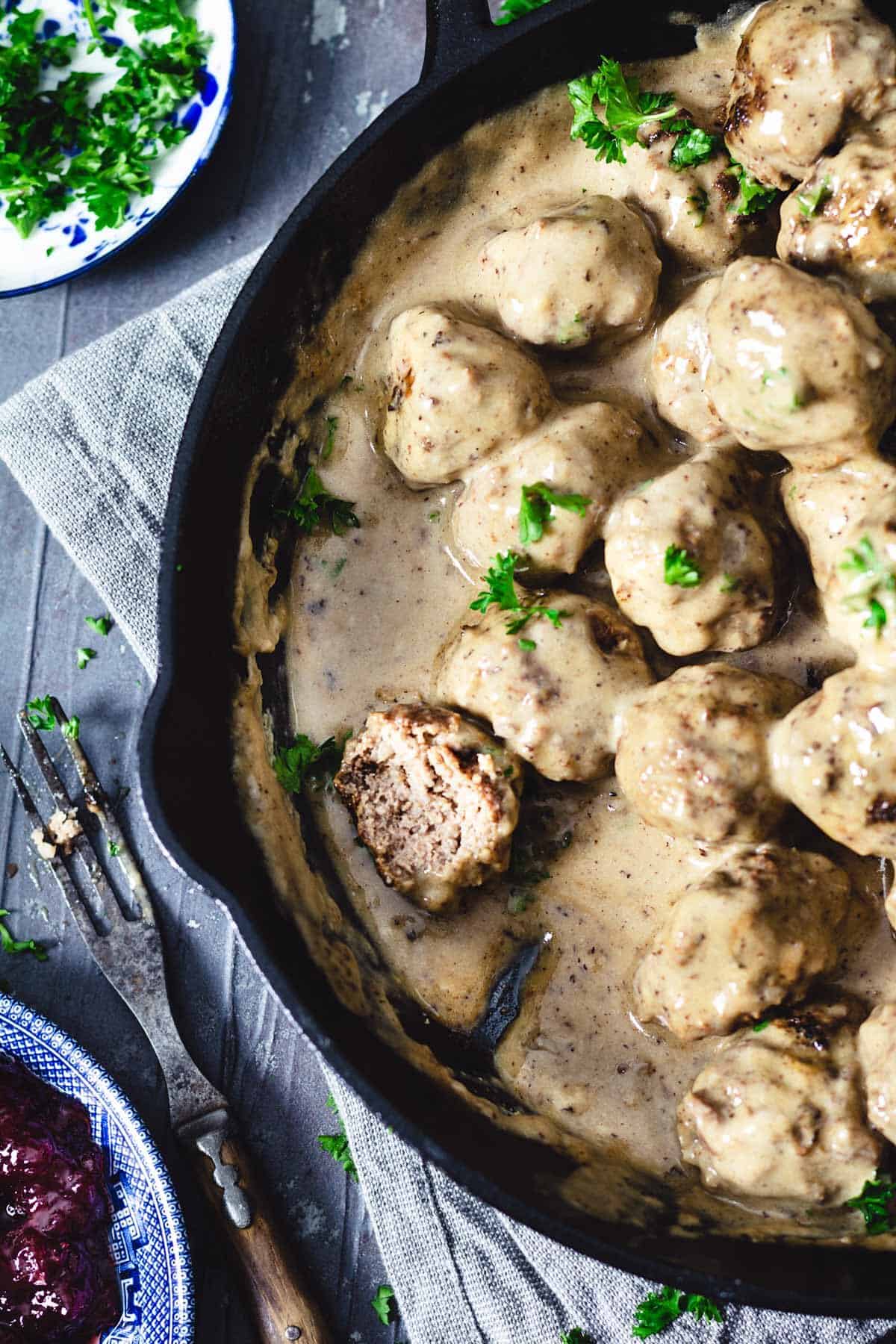 Meatballs in cream sauce with one meatball cut in half.