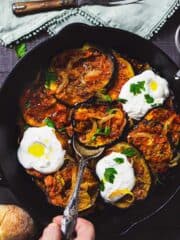 Skillet with Persian eggplant dish topped with garlicky yogurt.