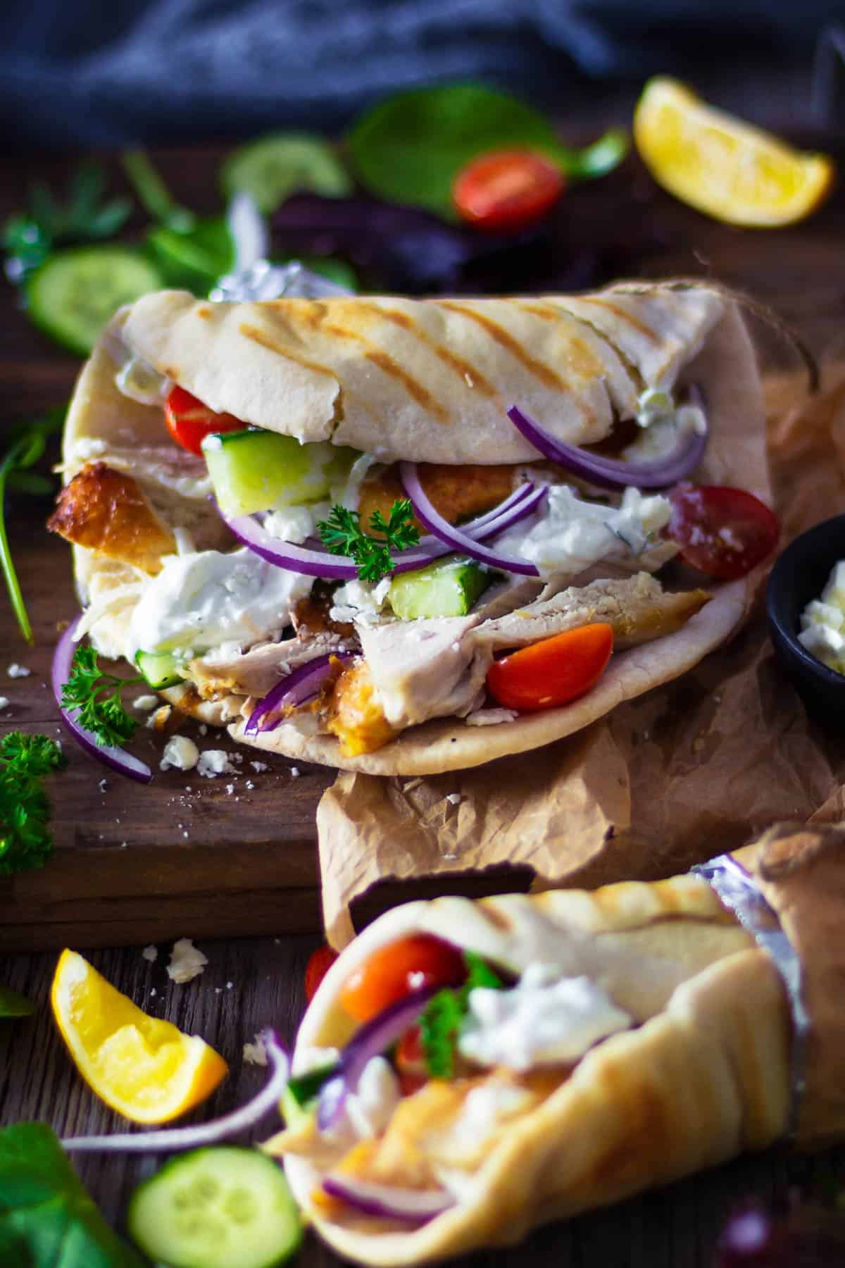 A close up of turkey gyro with feta cheese, tomatoes, red onions, cucumber, and Greek tzatziki.