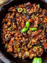 Eggplant caponata side dish in a cast-iron pan.