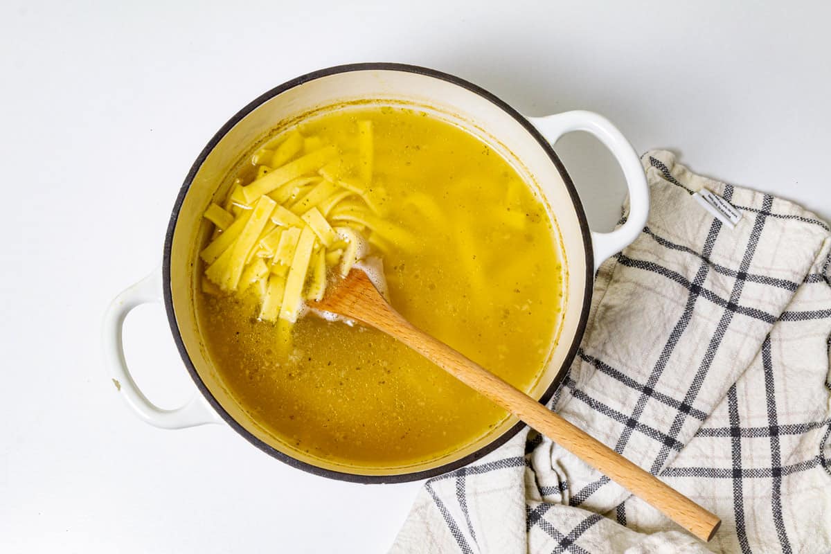 A pot with broth and noodles.