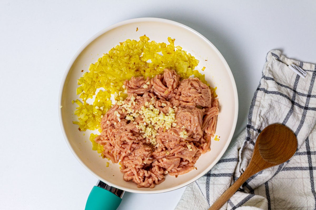 Onion, garlic, and ground chicken in a skillet.