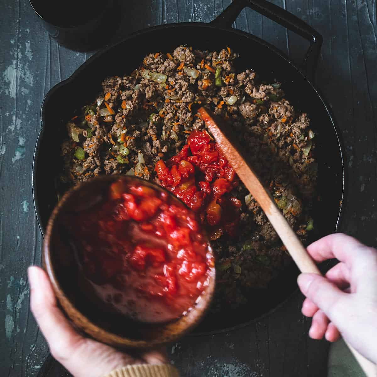 Adding tomatoes to the meat mixture. 