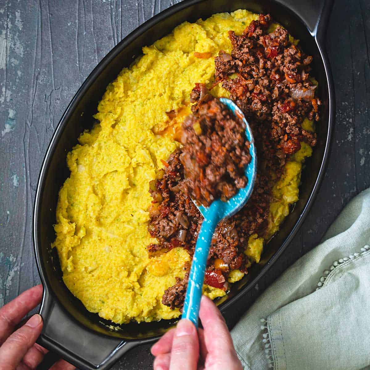 Layering meat over polenta in a casserole dish. 