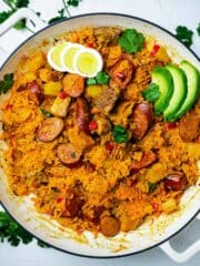 Sausage and pork risotto in a skillet with avocado and hard-boiled eggs.