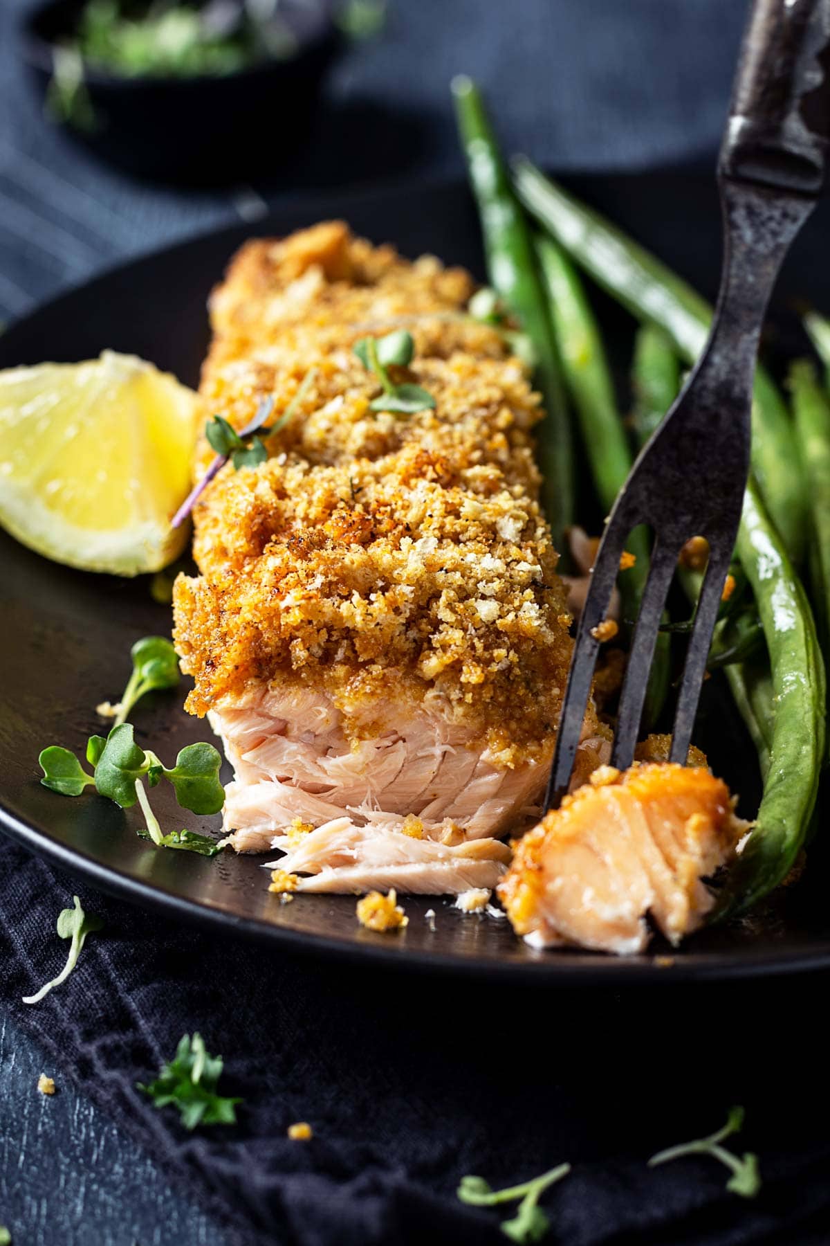 A close up of crusted salmon with a bite removed to show its flakiness.