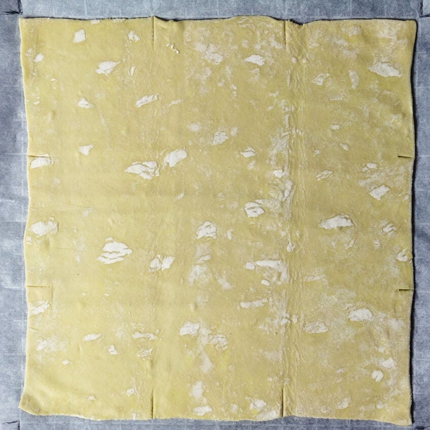 Rolled out puff pastry sheet into a square on a parchment paper.