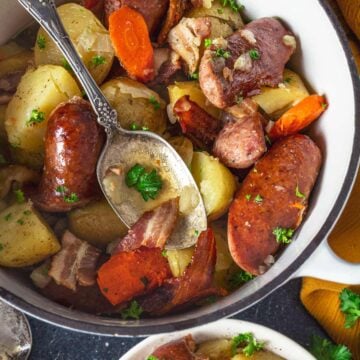 Irish coddle with sausage and potatoes in a white pot.