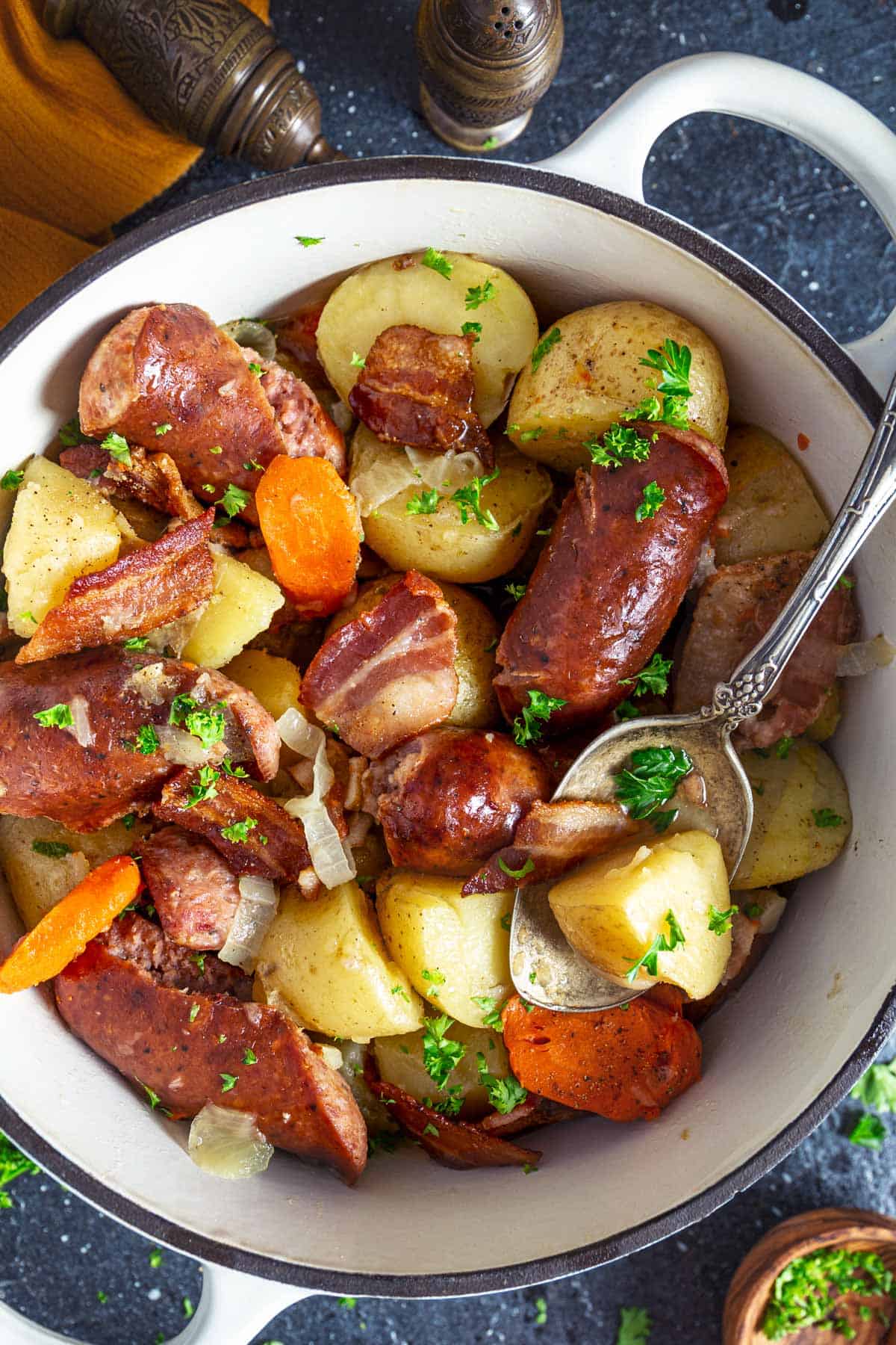 Irish sausage and potato stew in a Dutch oven with a serving spoon.