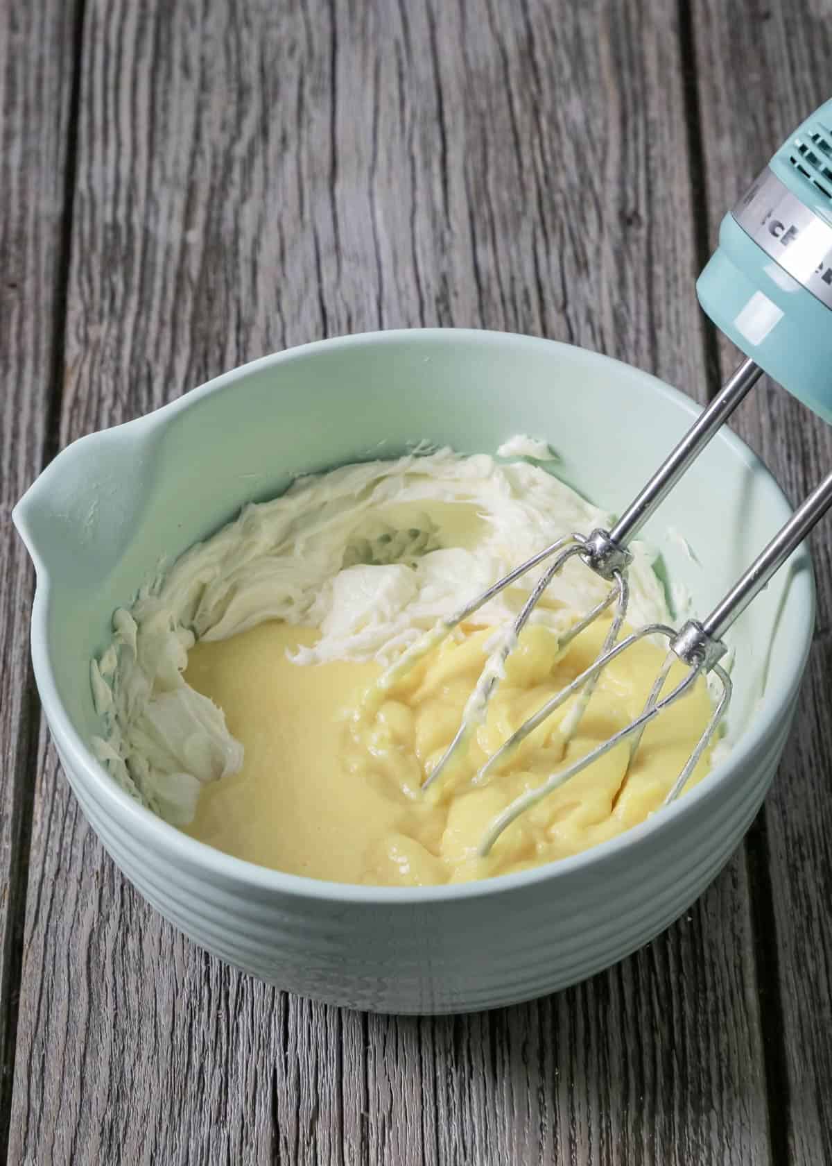 Mixing pudding with the butter in a bowl with a mixer.