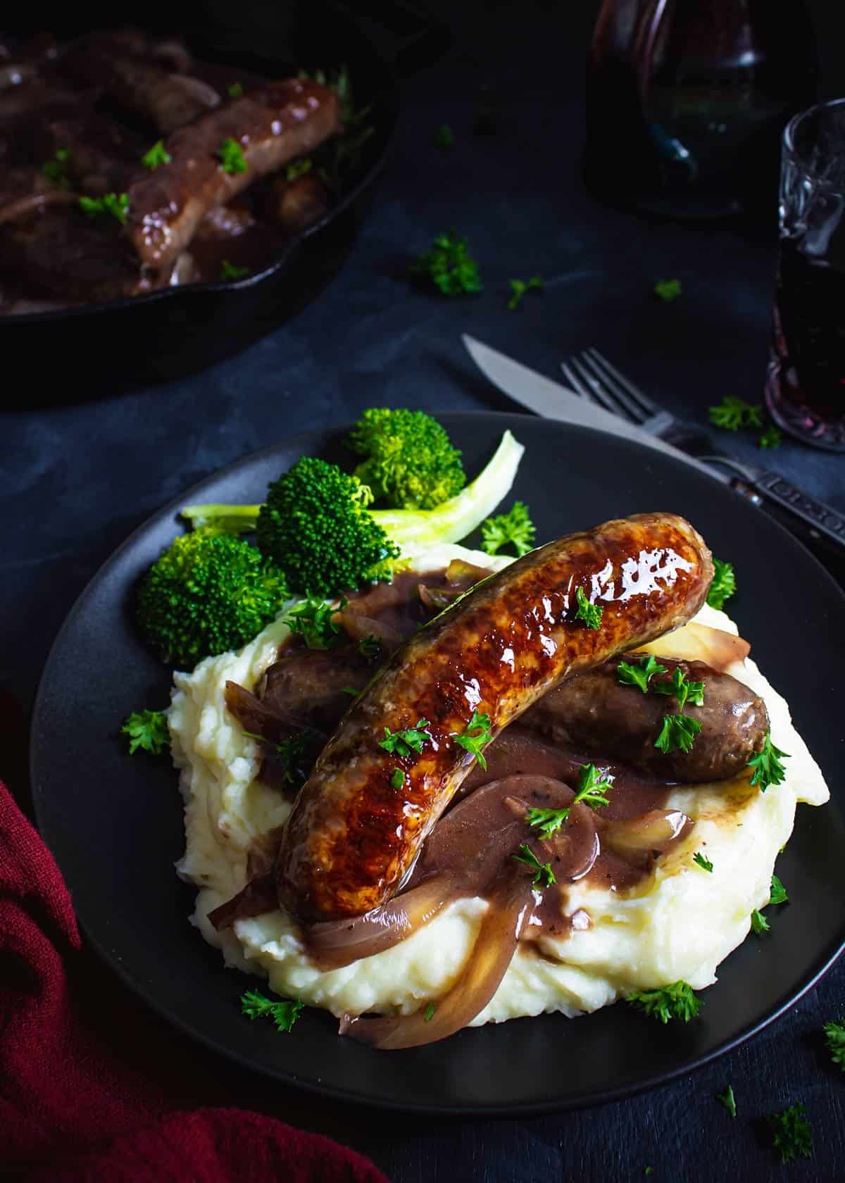 British bangers over mash and veggies on a plate.