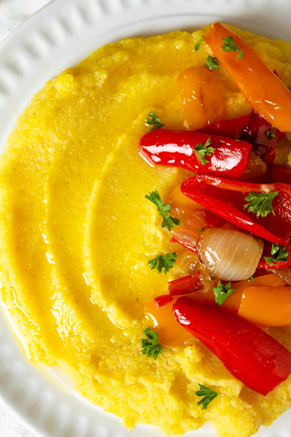 A close up of soft polenta with caramelized onions and peppers.
