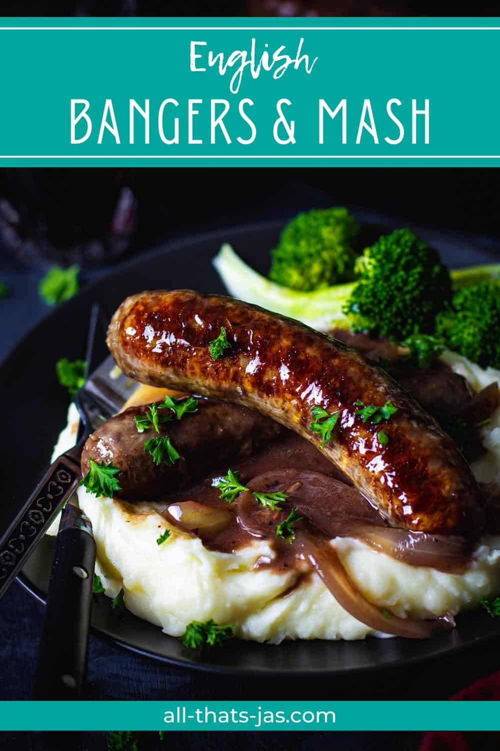 A close up of two banger sausages with onion gravy on top of mash and with text overlay.