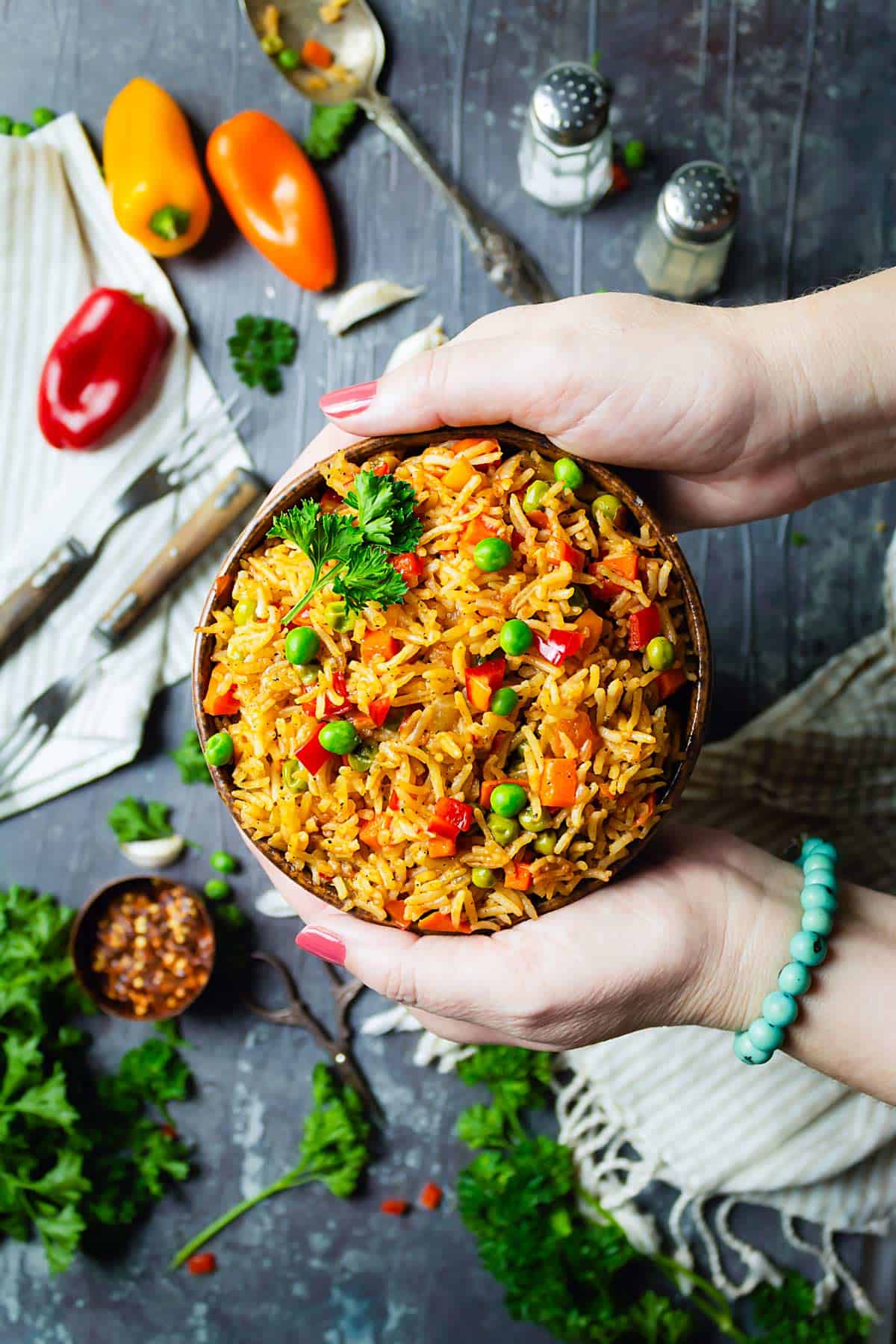 A person serving a bowl of mixed vegetable rice on the table.