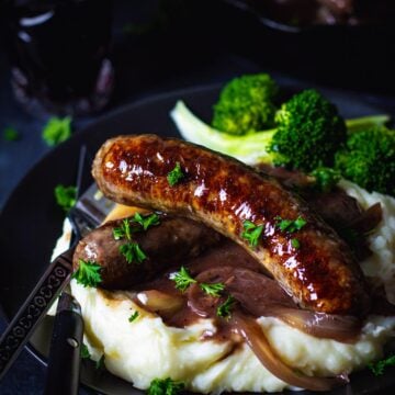 British bangers sausages in onion gravy over mustard mashed potatoes and broccoli.