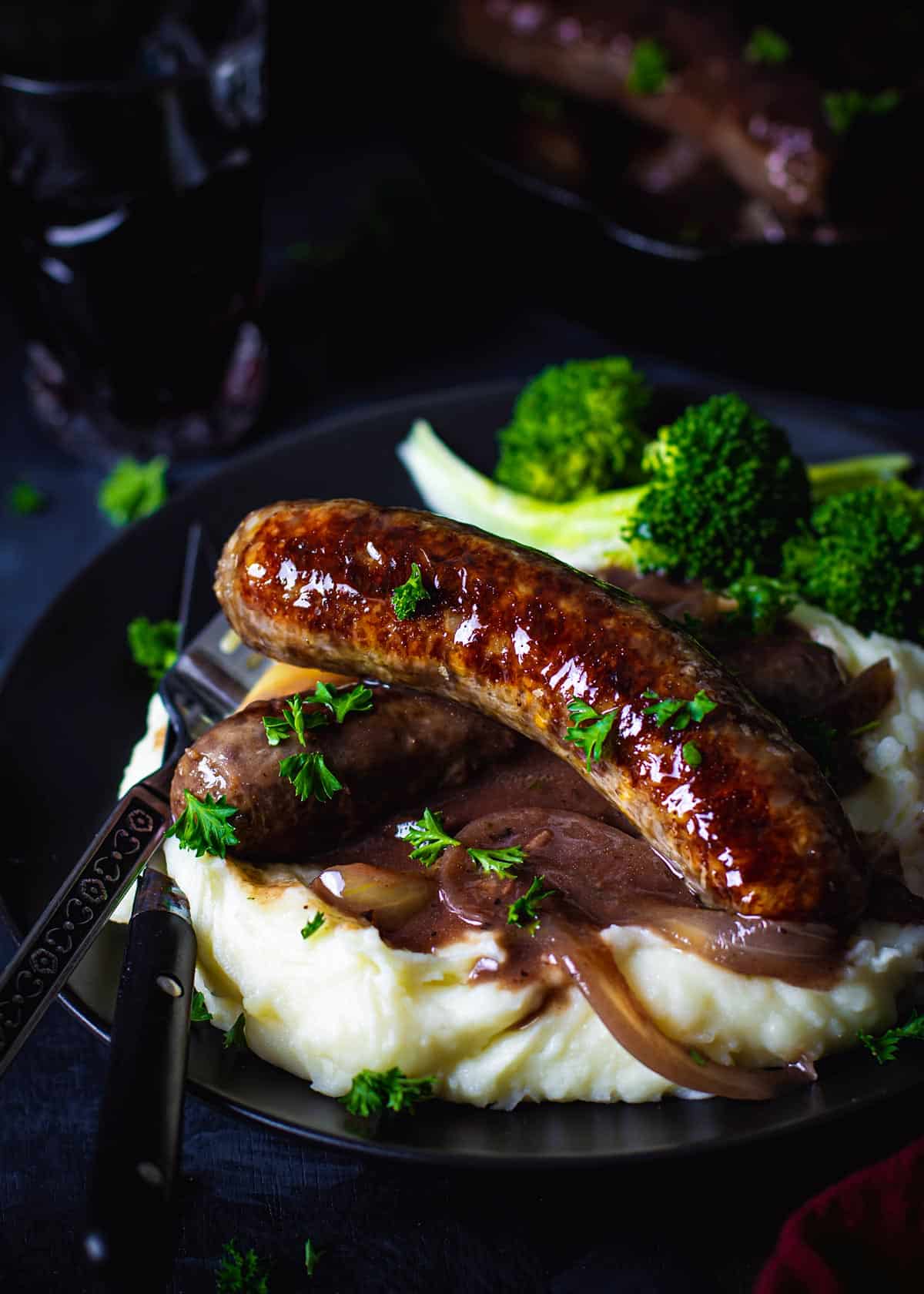 British bangers sausages in onion gravy over mustard mashed potatoes and broccoli.