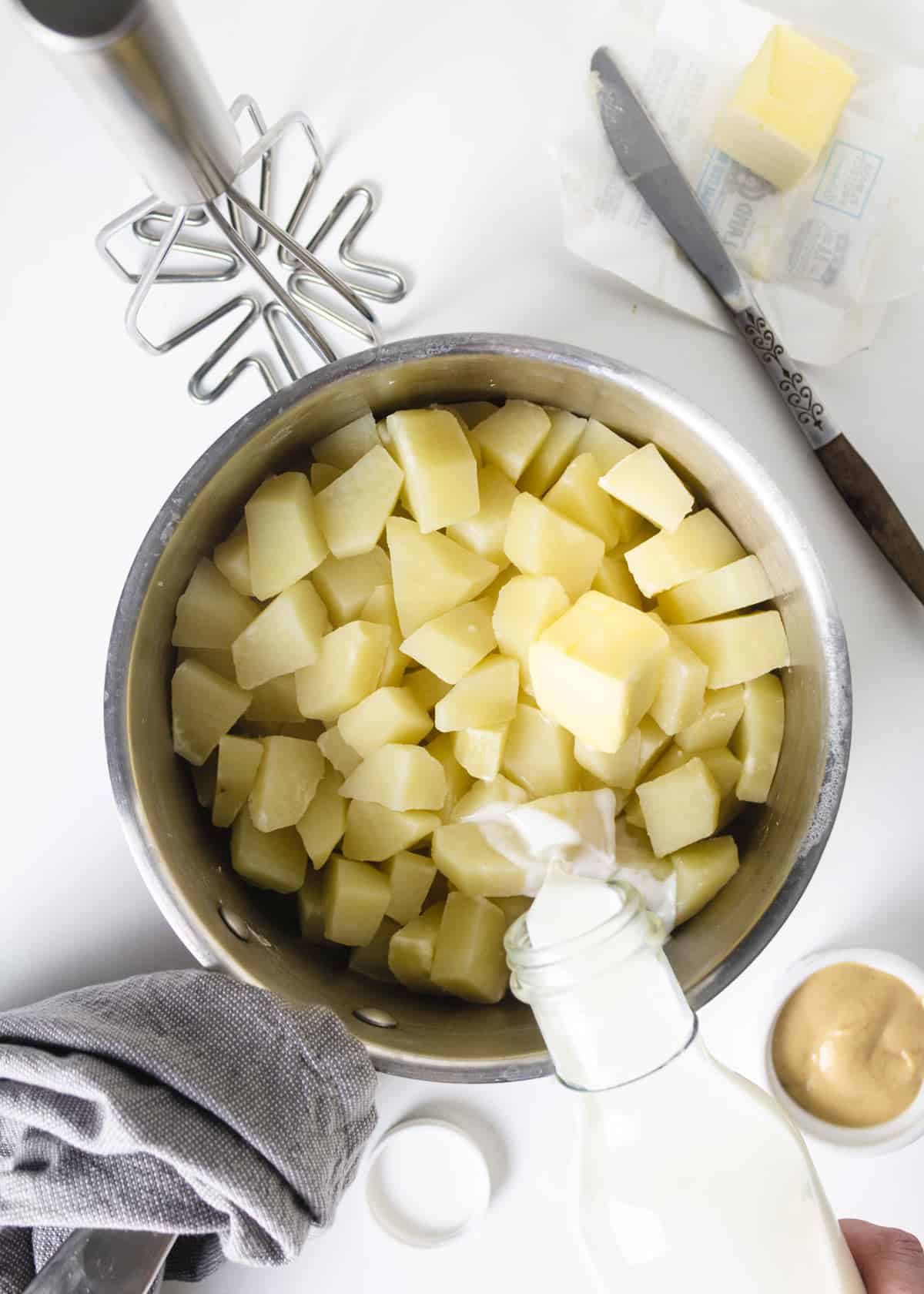 Mashing boiled potatoes with mustard, milk and butter.