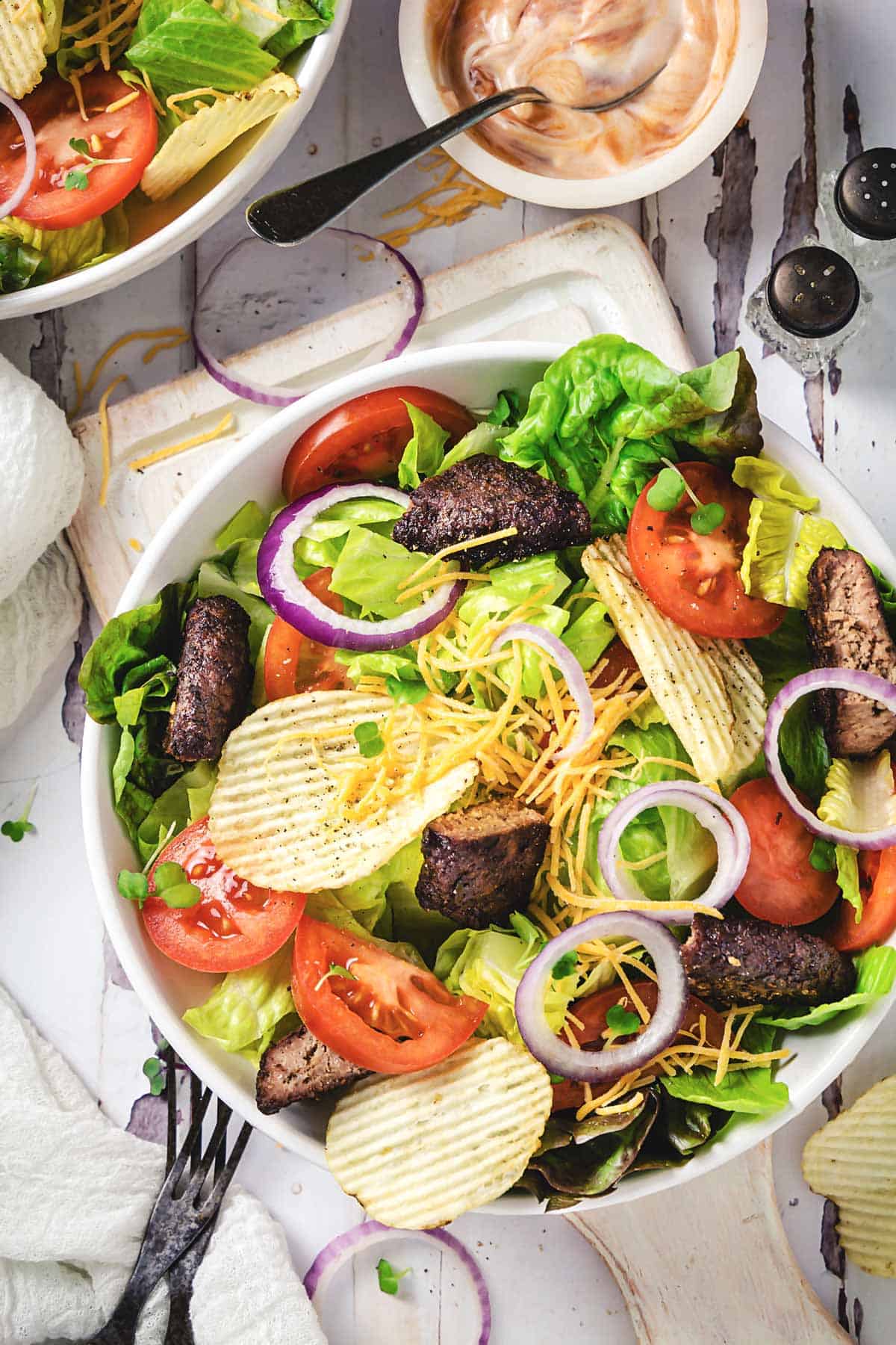 A bowl of cheeseburger salad topped with potato chips.