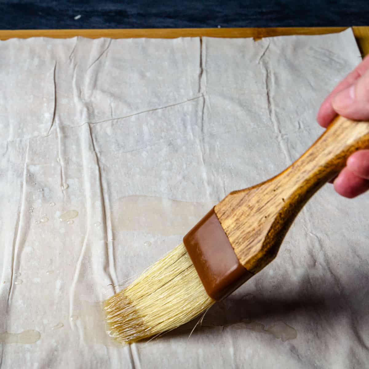 Oiling the filo sheet with pastry brush.