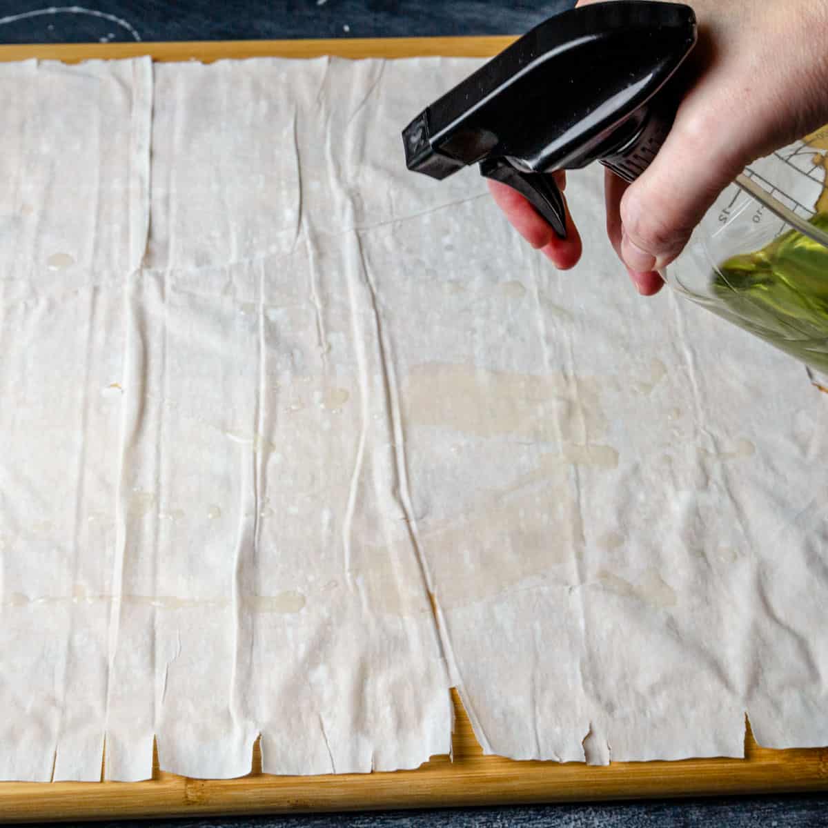 Oiling the filo with oil in a spray bottle.