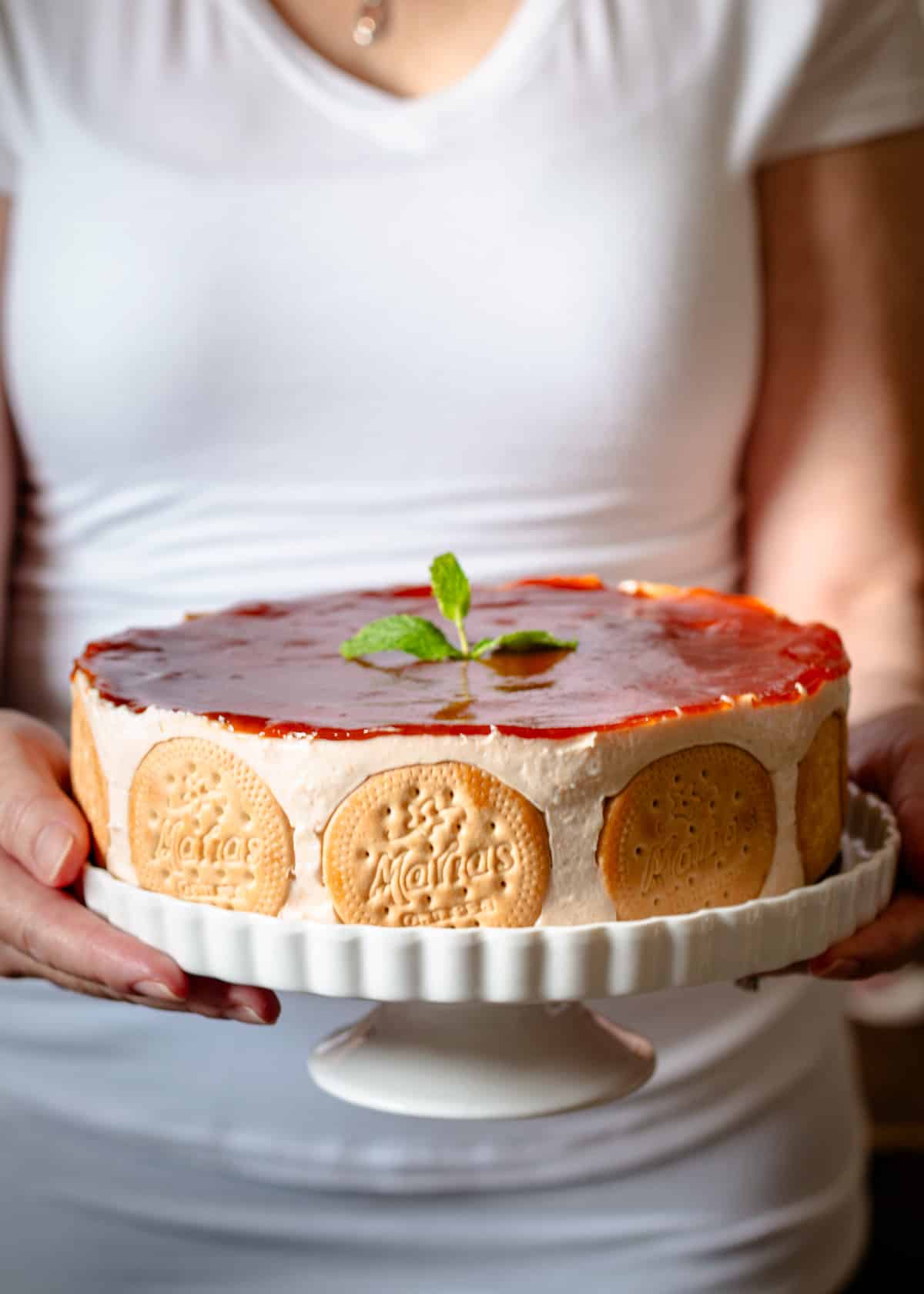 A woman holding cake stand with Mexican guava Carlota cake.