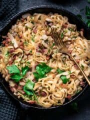 Fried cabbage and noodles with bacon in a skillet with fork.