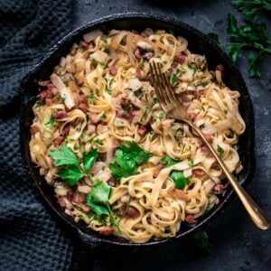 Fried cabbage and noodles with bacon in a skillet with fork.