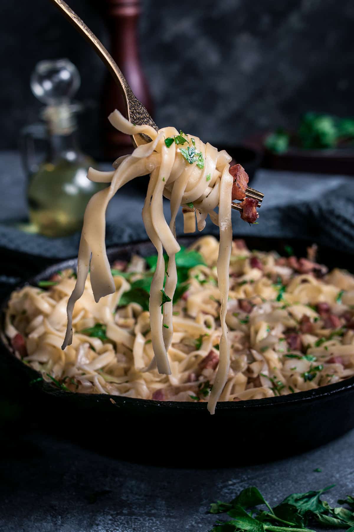Noodles with fried cabbage and bacon wrapped around a fork.