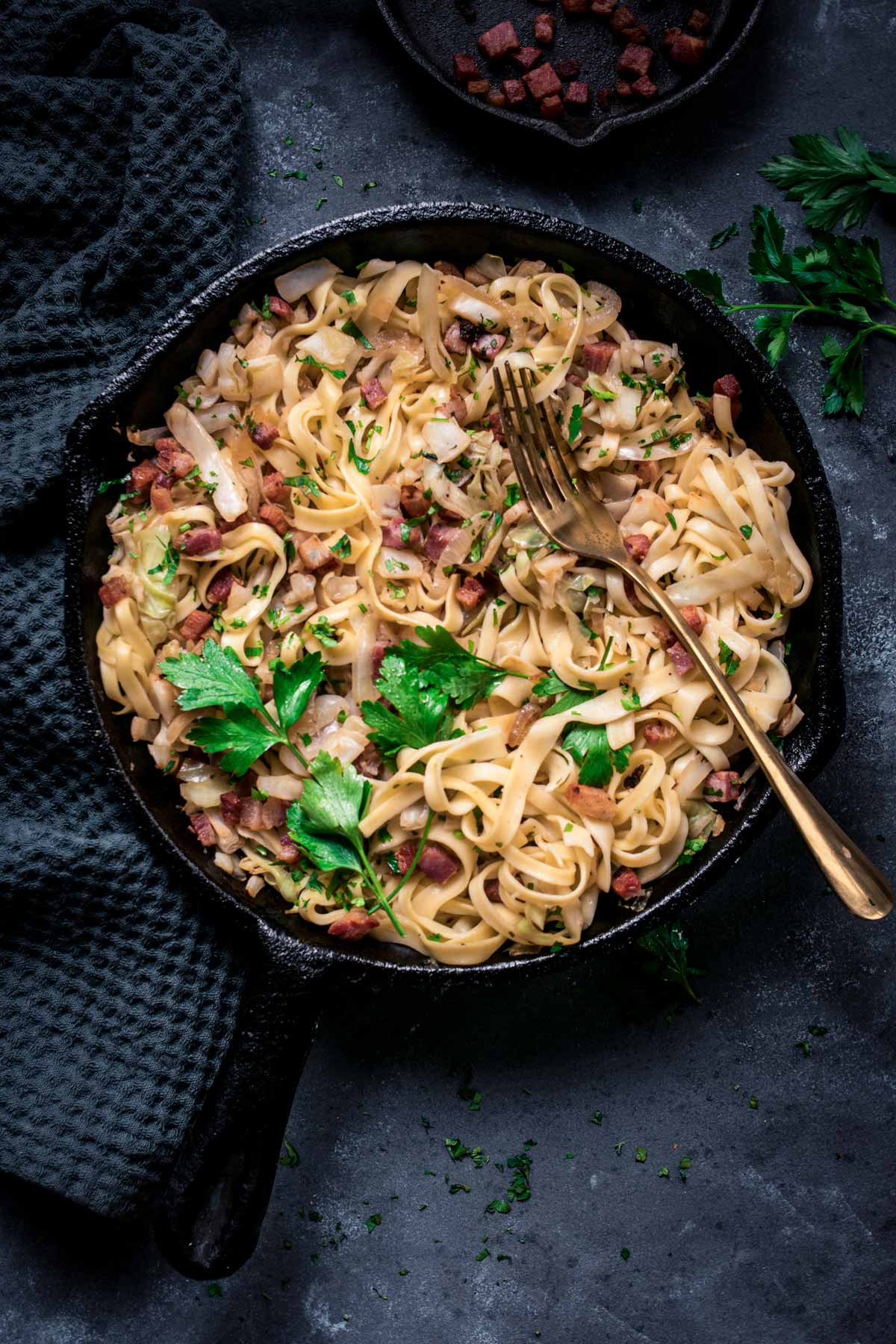 Fried cabbage and noodles with crispy bacon in a skillet.