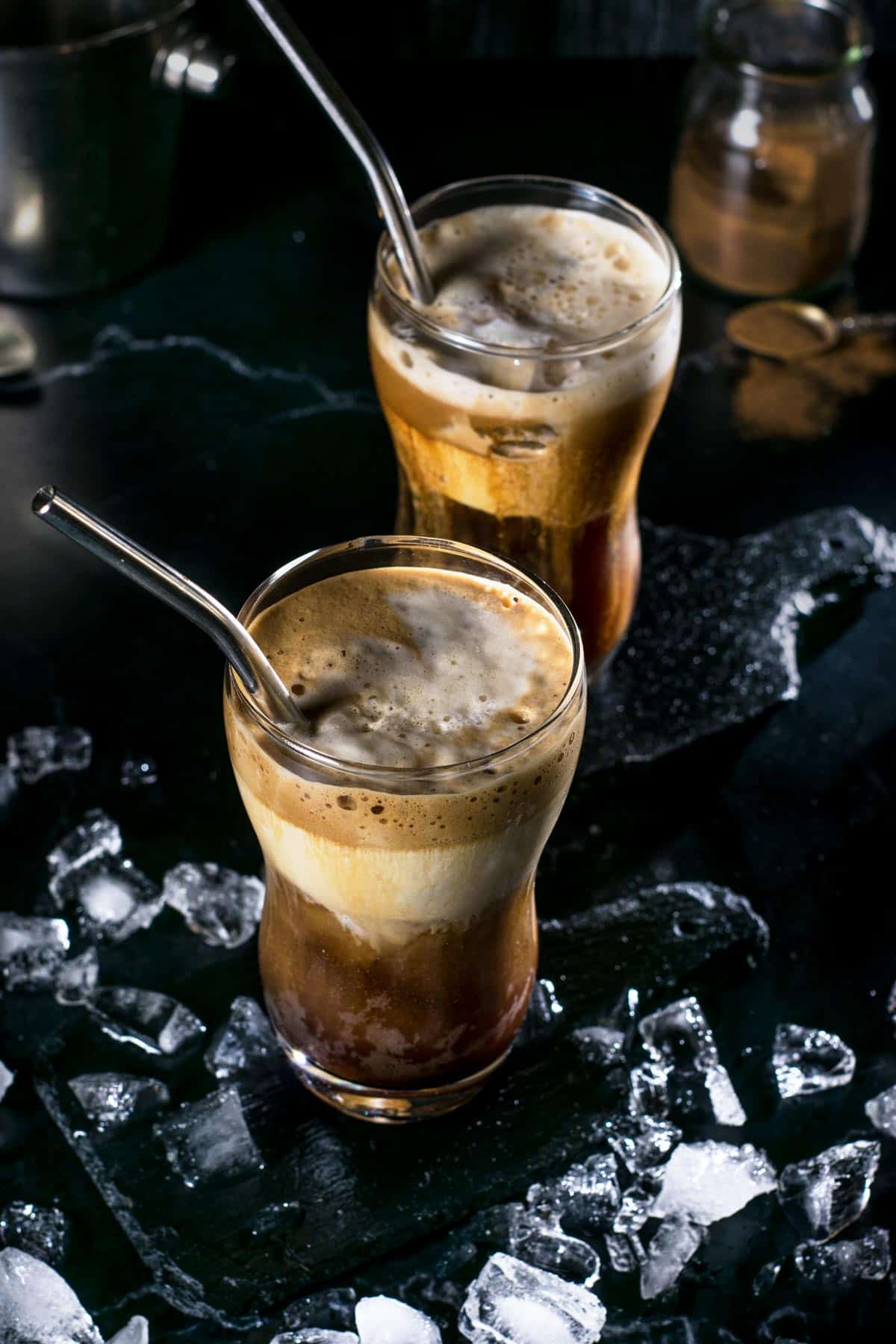 Overhead shot of classic Greek frappe in two glasses with straws and ice.