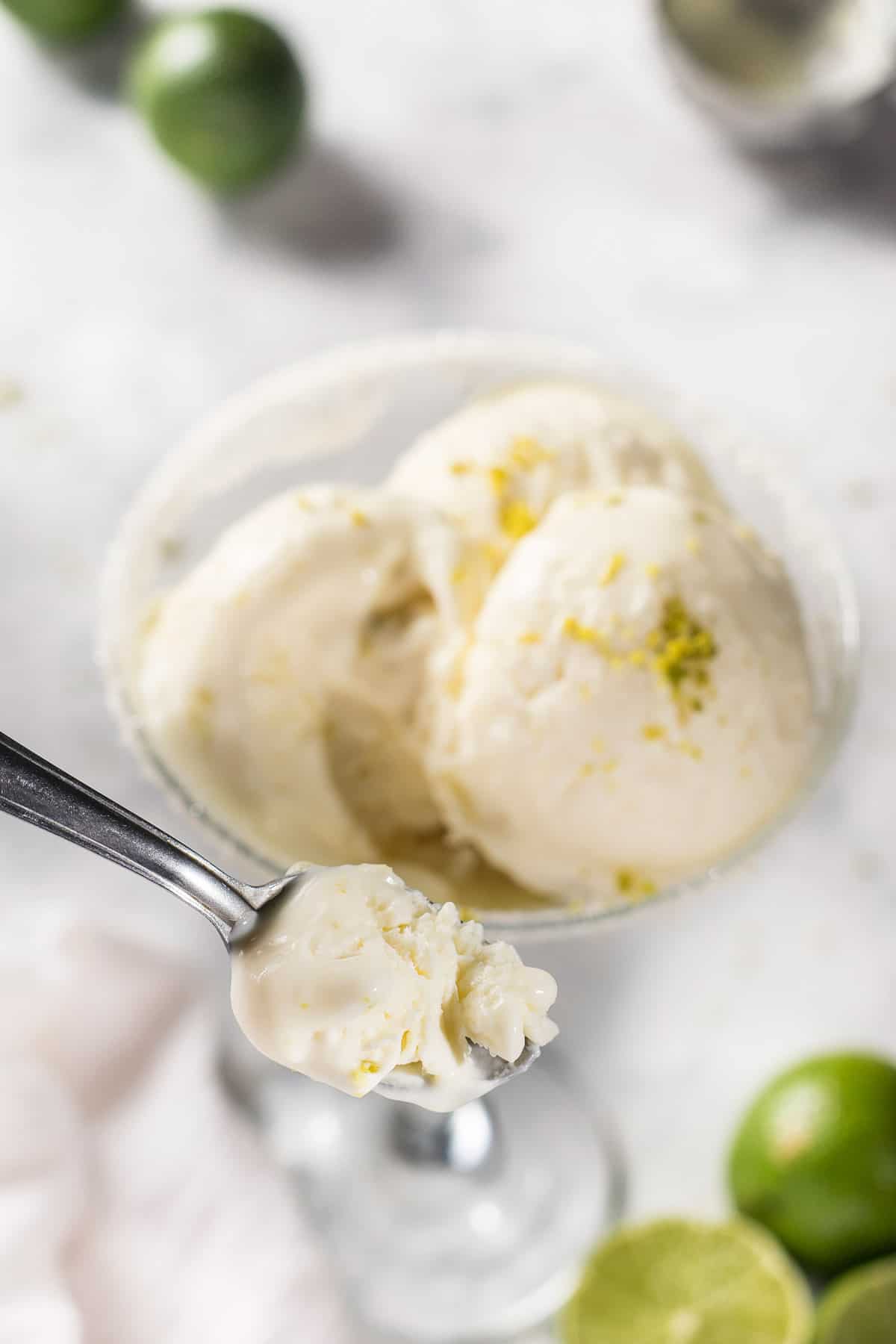 Overhead view of margarita ice cream in a spoon over scoops in a glass.