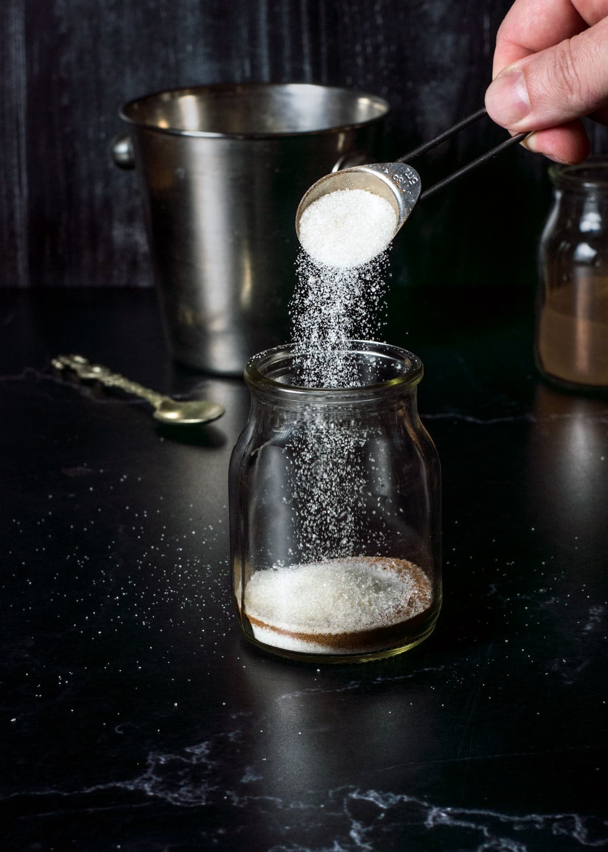 Adding sugar to a jar with instant coffee to make frappe.