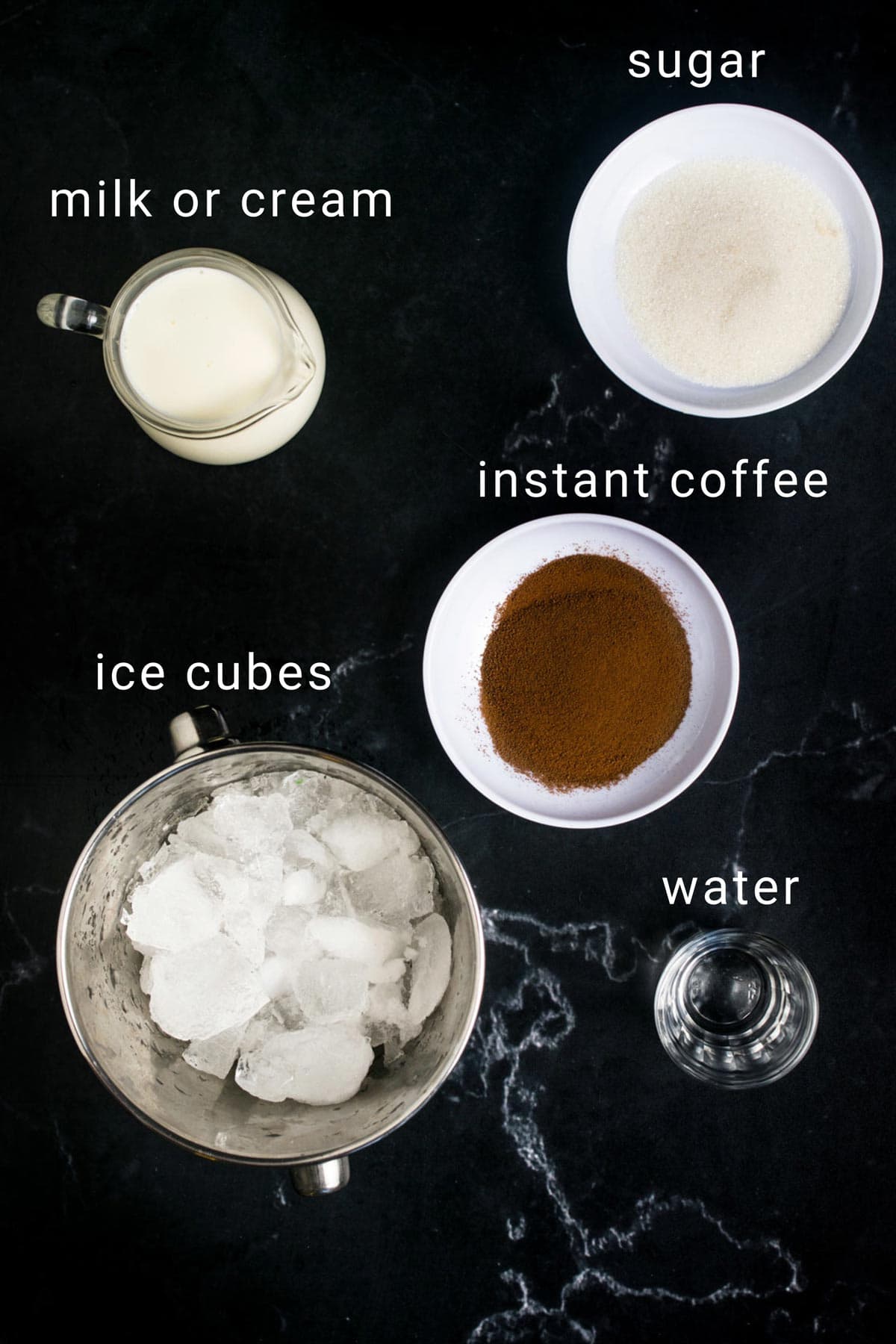 Ingredients for iced coffee frappe on a black counter.