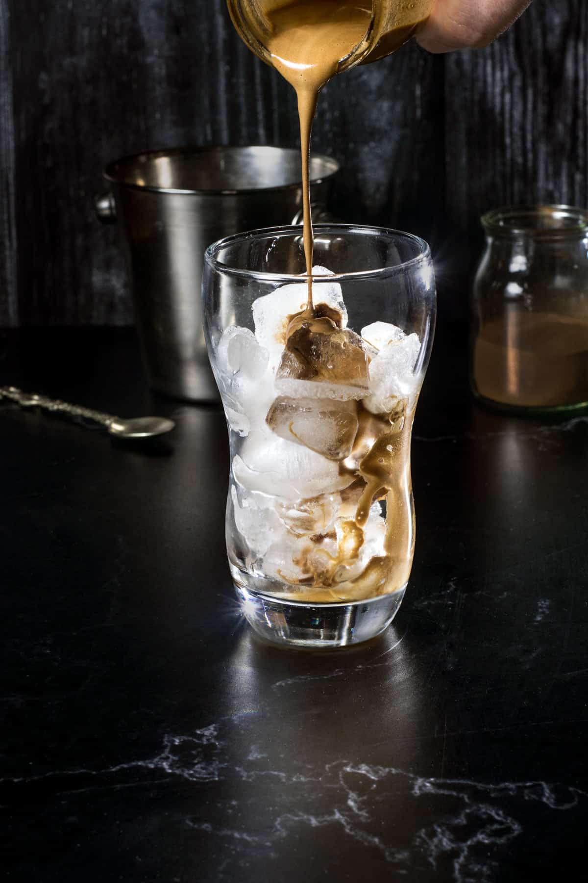 Pouring the foamy layer over ice cubes in a glass.