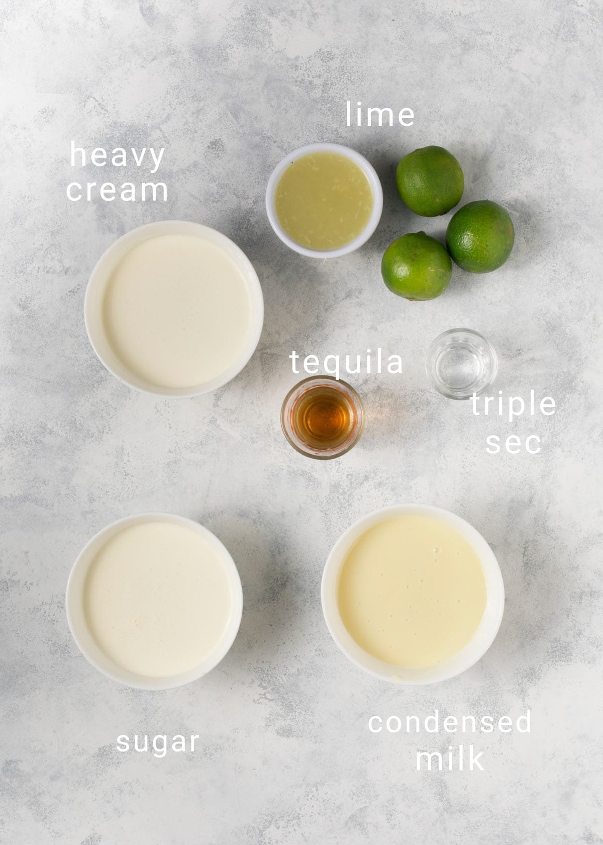 Ingredients for margarita ice cream on a counter, including tequila and lime. 