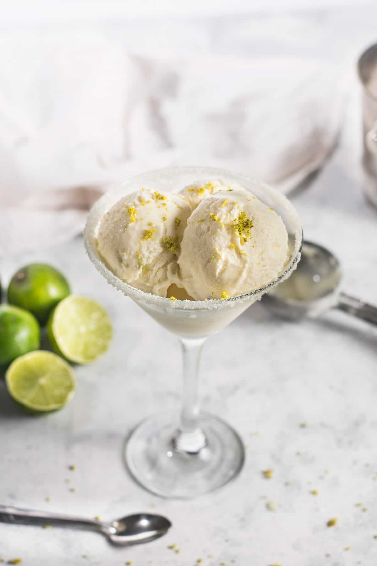 A glass with scooped margarita ice cream and lime on a white background.