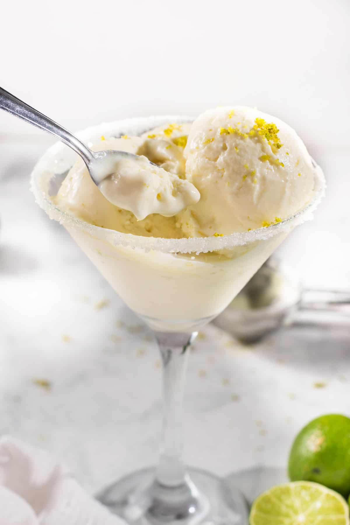 Scooping out margarita ice cream with a spoon from a glass. 