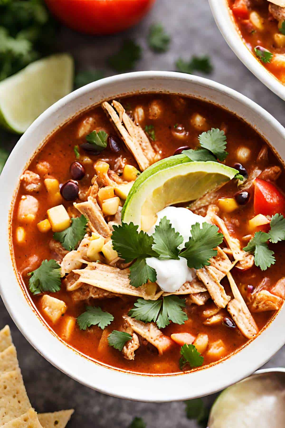 A bowl of Mexican chicken tortilla soup topped with avocado and cilantro.