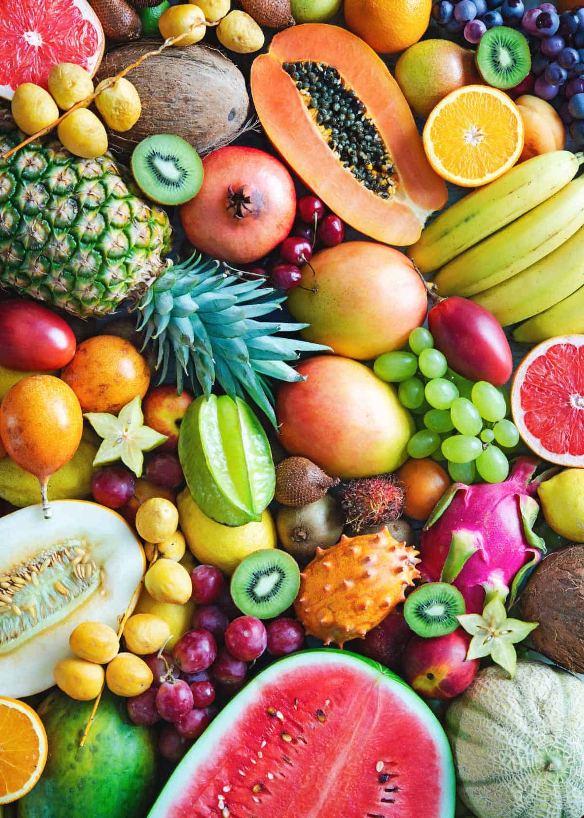 A beautiful mix of fruits, some halved to show the seeds, some whole.