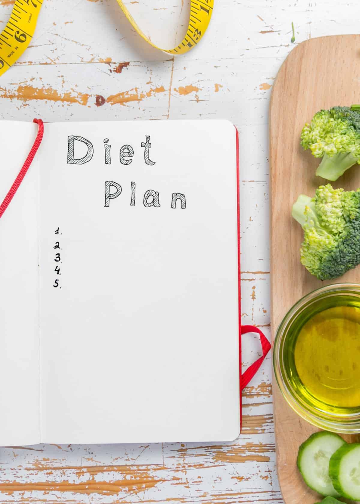 A note book on a table with a diet plan line written in it.
