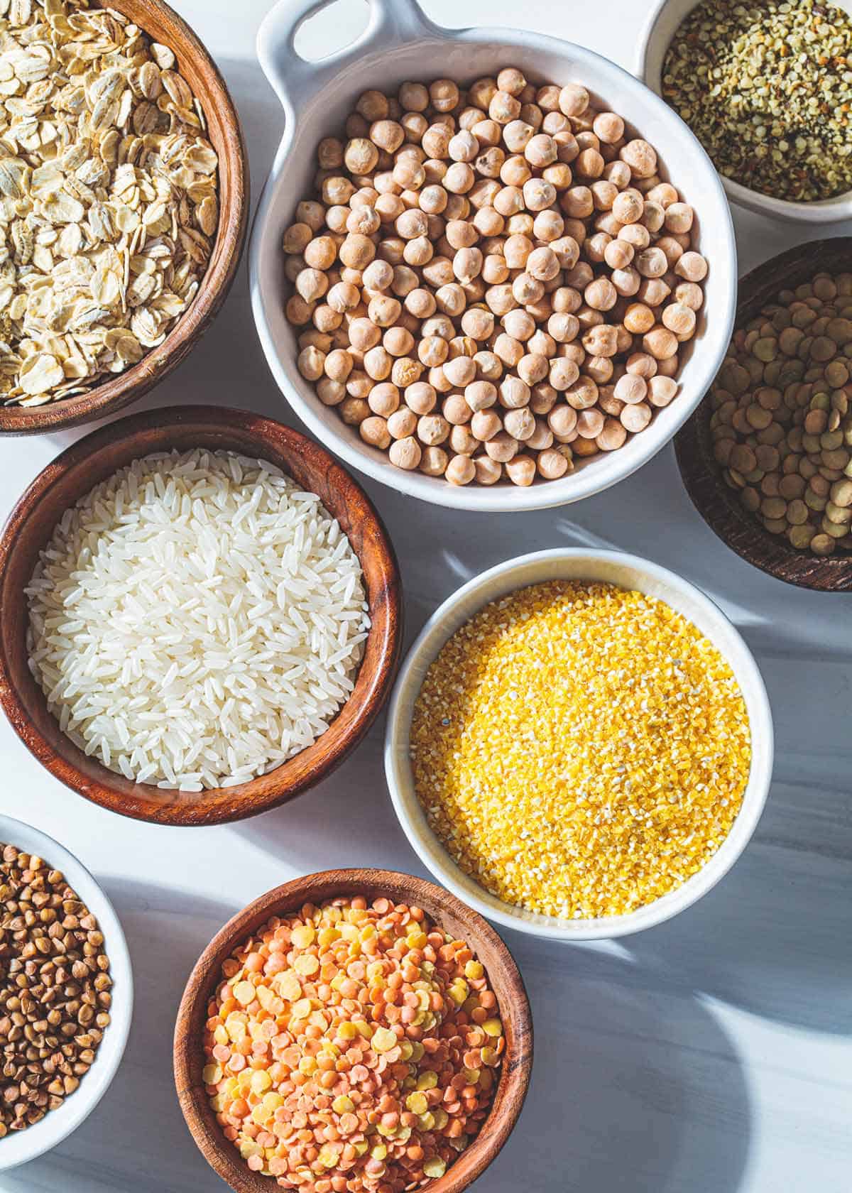 Bowls with starchy food such as rice and legumes on a table.