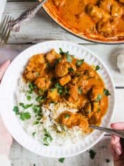 Chicken tikka masala with rice in a bowl and garnished with cilantro.