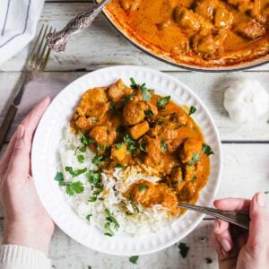 Chicken tikka masala with rice in a bowl and garnished with cilantro.