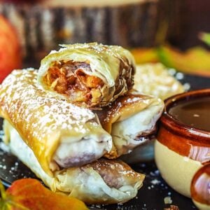 Stacked apple pie filo rolls with the top one being split in half to reveal the filling.