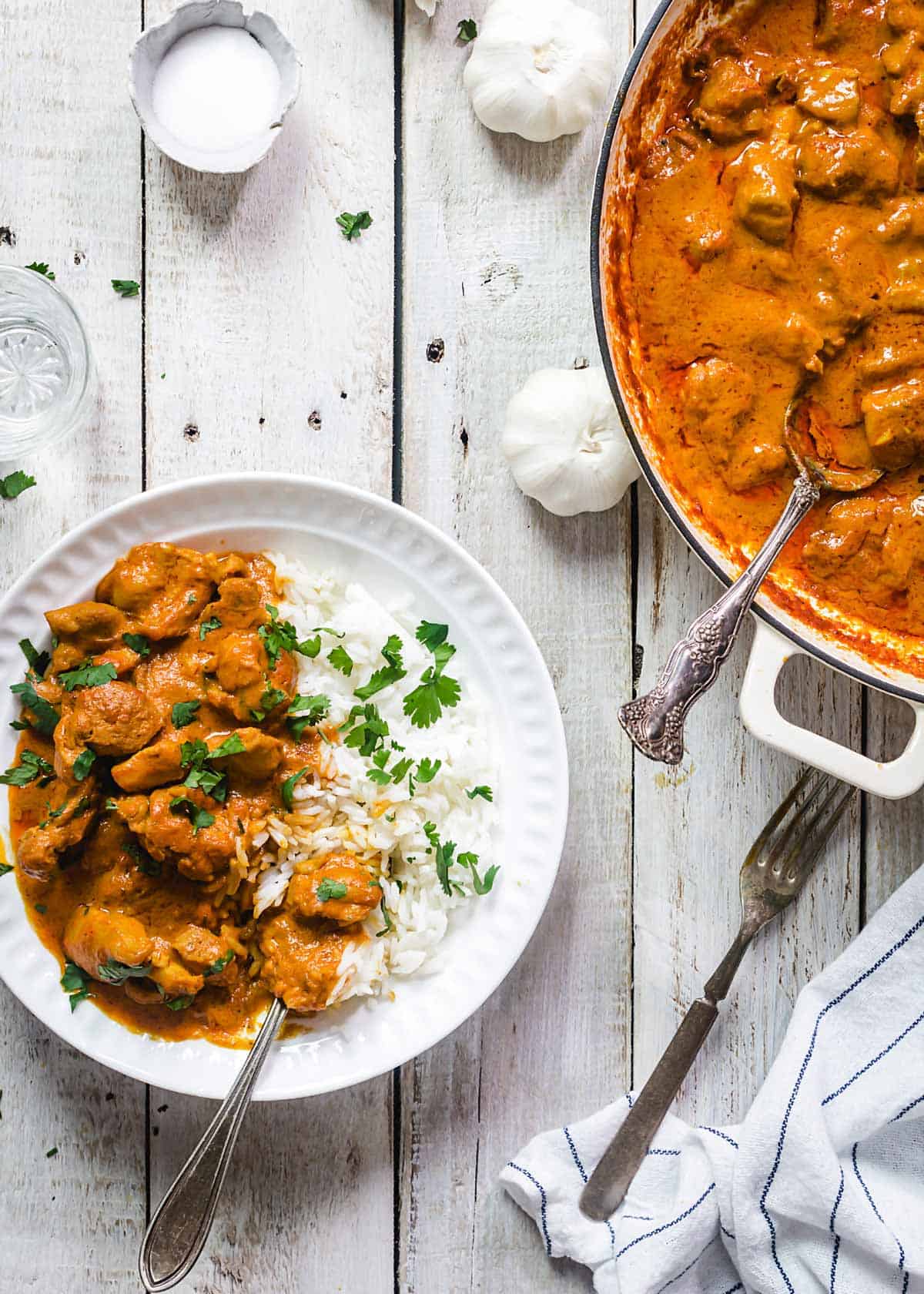 A bowl and a pan with chicken tikka on a table.