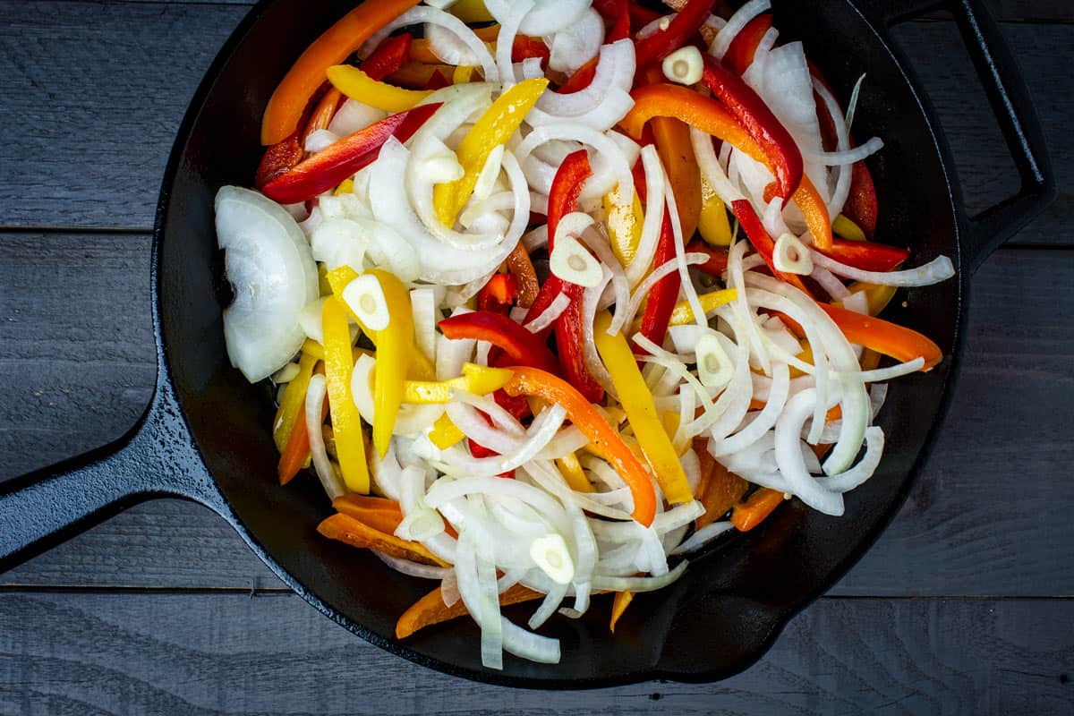 Onions and bell pepper strips sautéing in a skillet. 